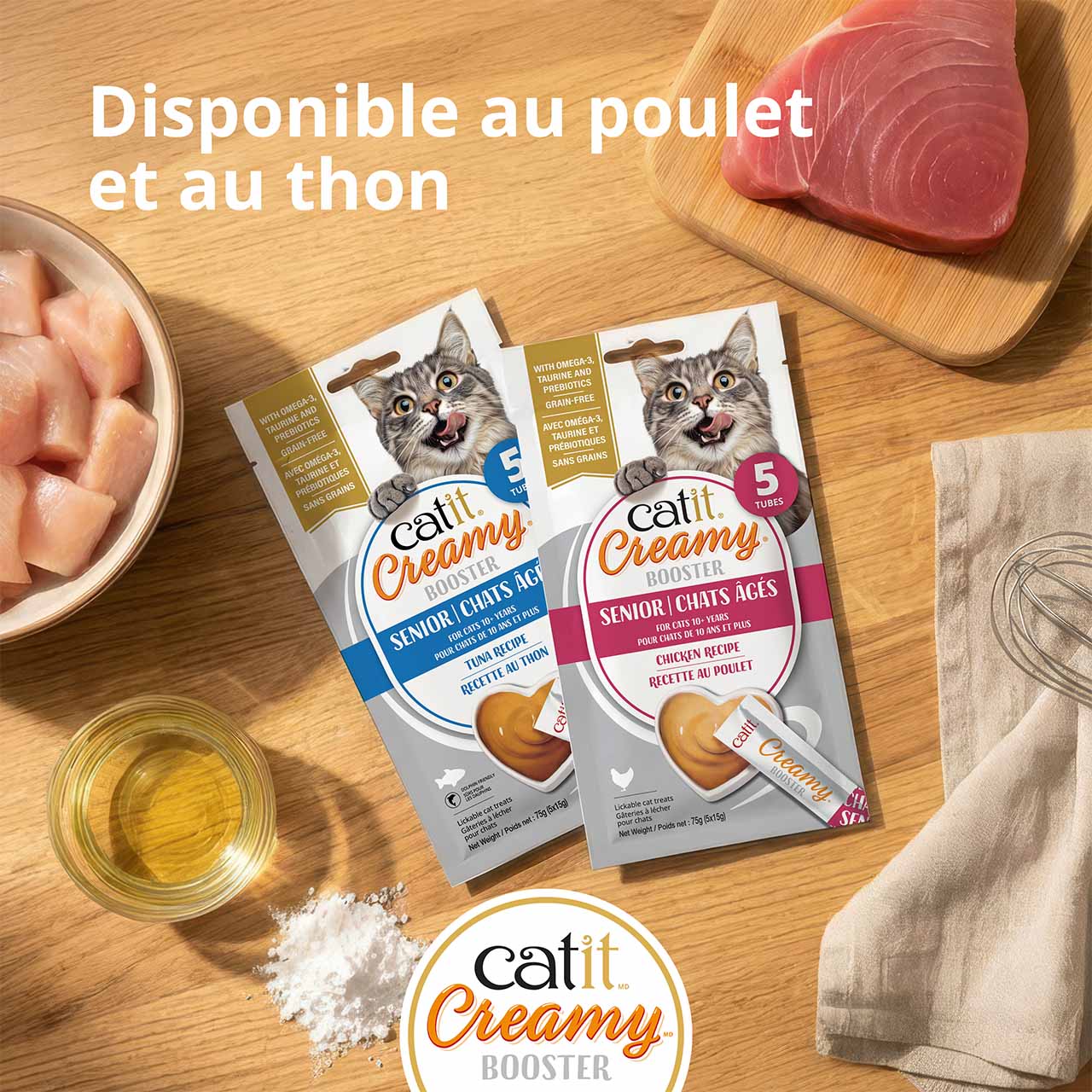 Emballages de gâterie Catit Creamy Booster pour chatons déposés sur un comptoir en bois et entourés d’ingrédients, vue de dessus