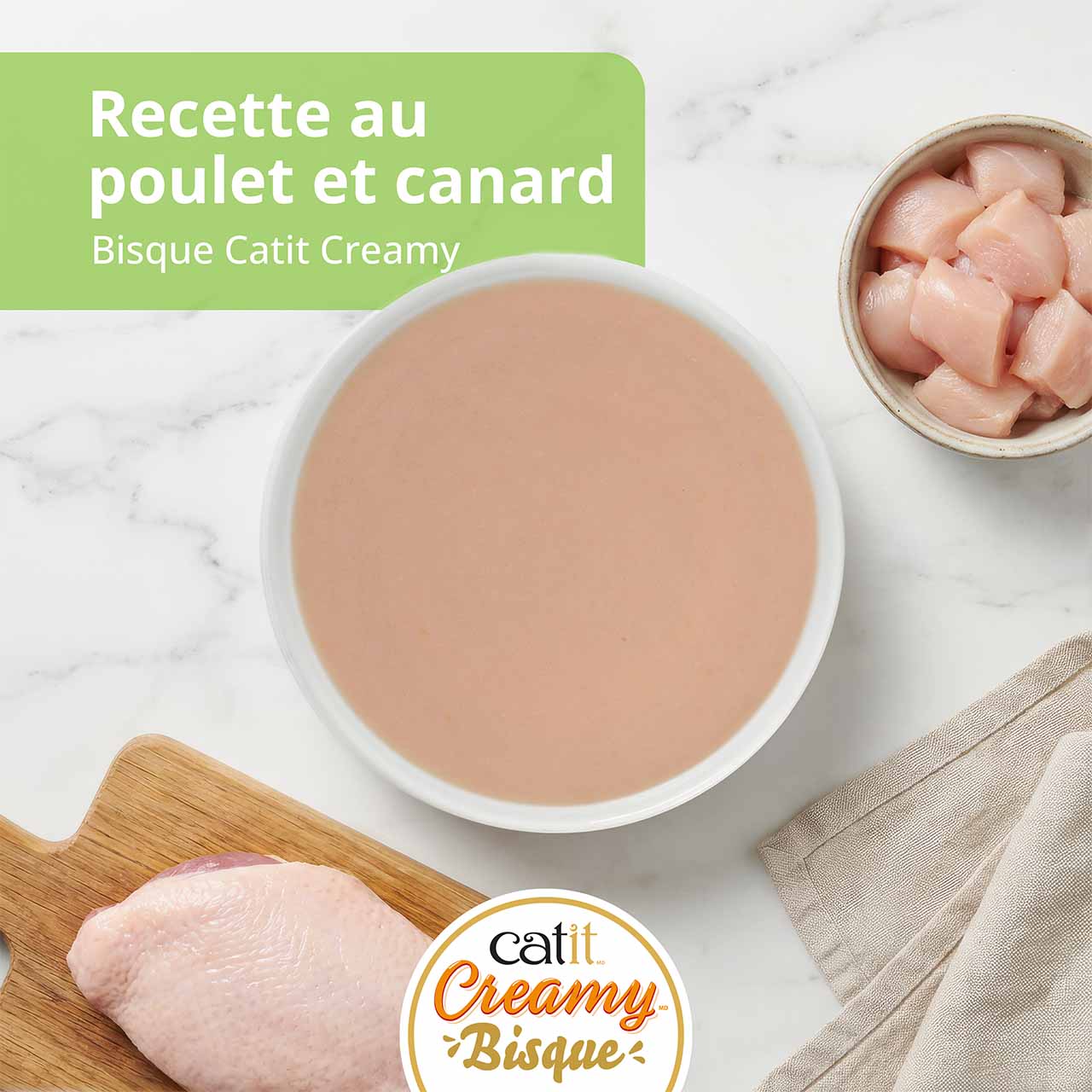 Gâterie bisque Catit Creamy au poulet et canard pour chats, présentée avec un bol de bisque, du poulet cru et une poitrine de canard
